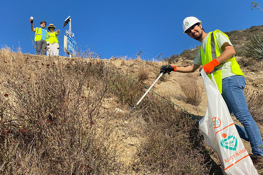 Three Takataka volunteers in yellow vests cleaning up trash