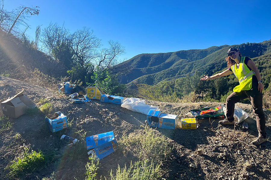 Volunteer in yellow vest pointing at mountain trash